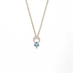 Crescent moon charm necklace with a trillion aquamarine and diamond pendant on a white background | Camille Torres Designs