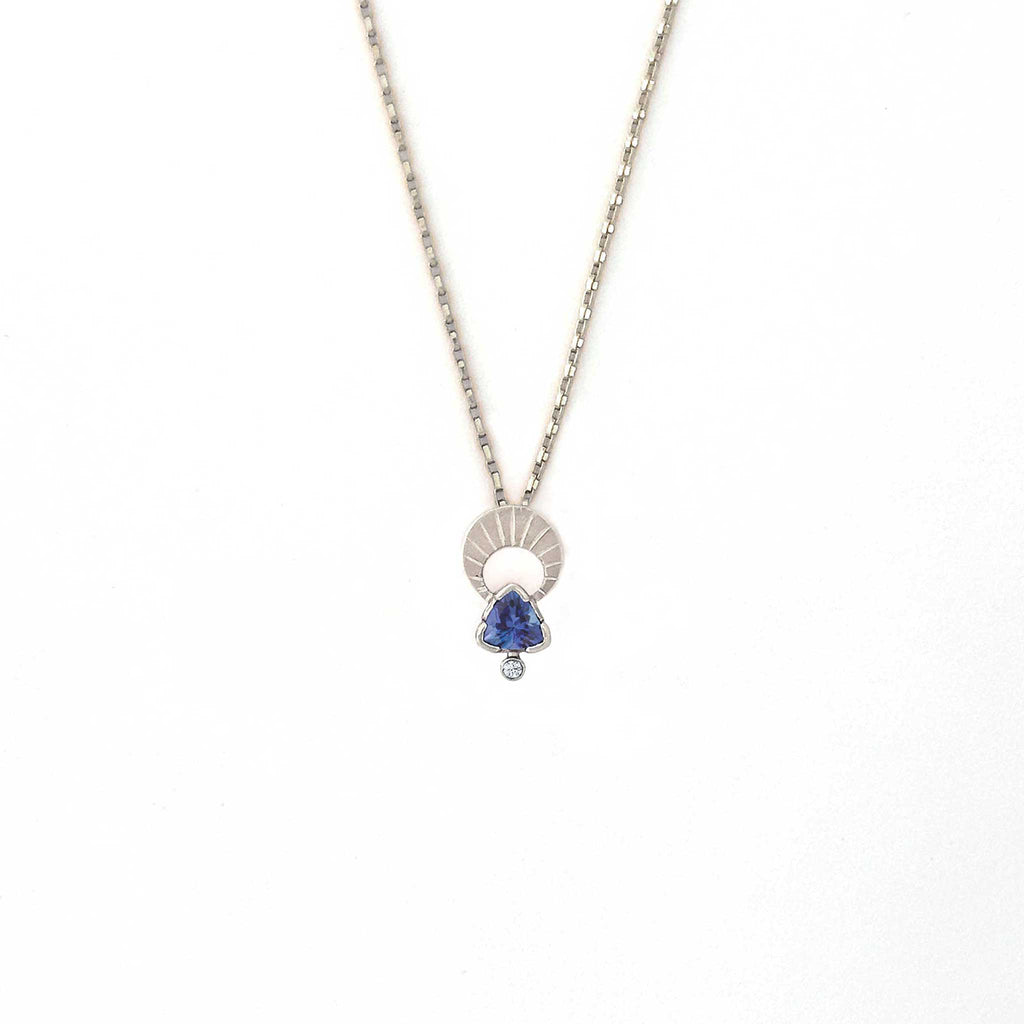Crescent moon charm necklace with a trillion tanzanite and diamond pendant on a white background | Camille Torres Designs