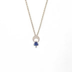 Crescent moon charm necklace with a trillion tanzanite and diamond pendant on a white background | Camille Torres Designs