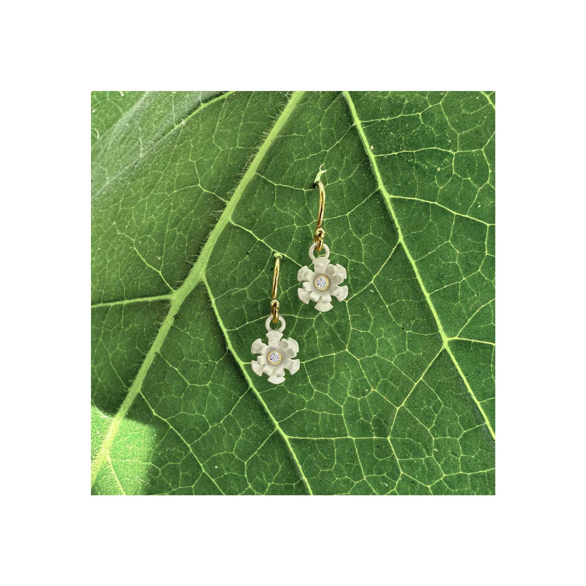 Blossom dangle earrings with matte white silver petals and 1.7 mm diamond, gold filled ear wires, on leaf