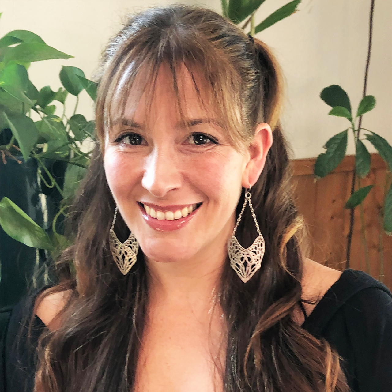 Camille Torres with long brown hair and her sterling silver Slumber design earrings.