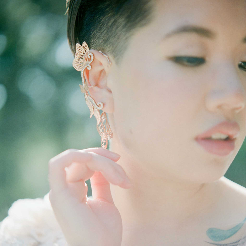 Bespoke bridal butterfly earring with rose gold and white sapphire in front os a blurred background | Camille Torres Designs