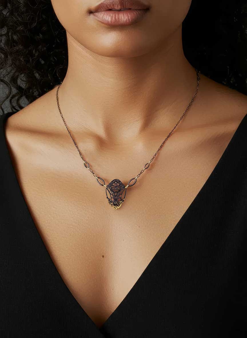 Cocoon butterfly pendant 24k gold black silver necklace worn by a person against a black background