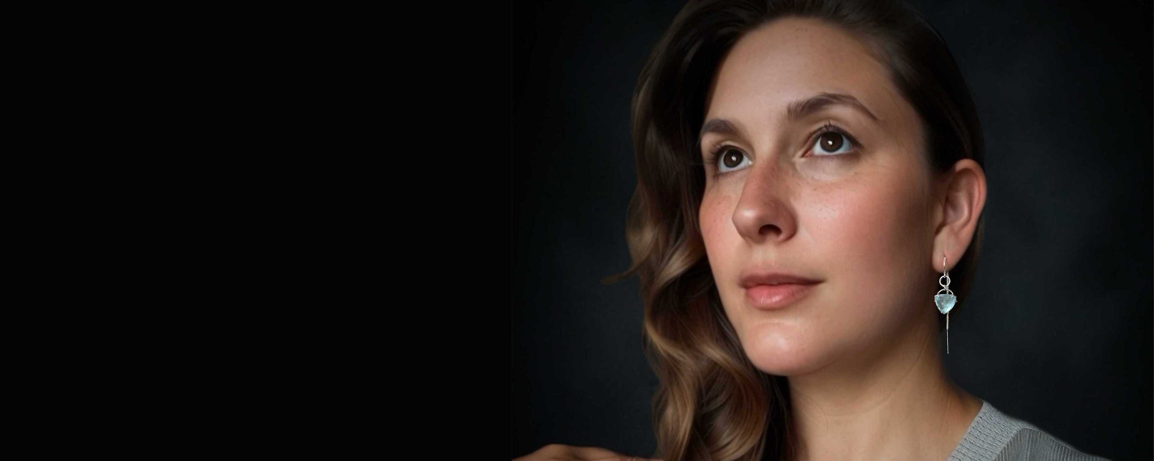 Woman with blue topaz threader earrings a dark background