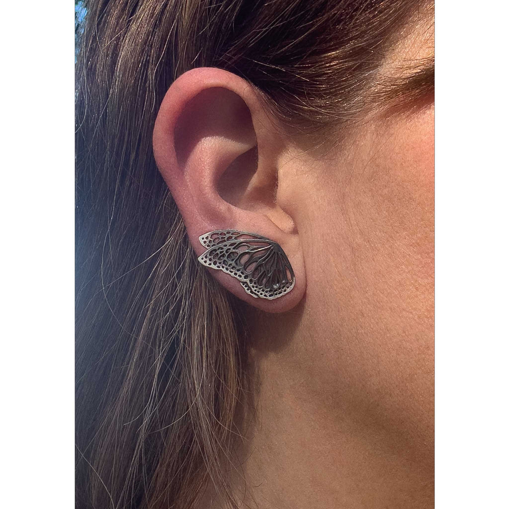 Close-up of ear wearing an oxidized silver Flight butterfly wing ear climber 
