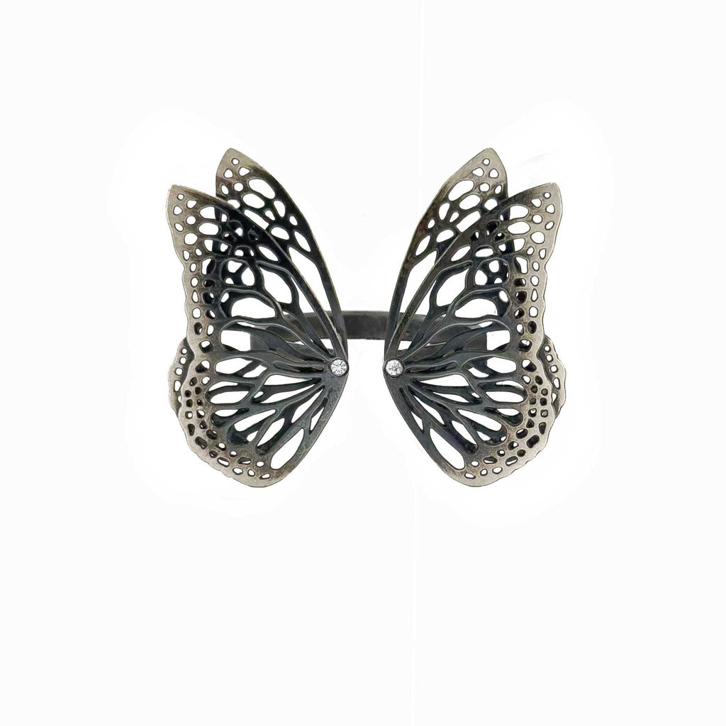 Migration butterfly ring in oxidized sterling silver with intricate cutout wing pattern, 1-inch adjustable band and Diamond accents over a white background | Camille Torres Designs