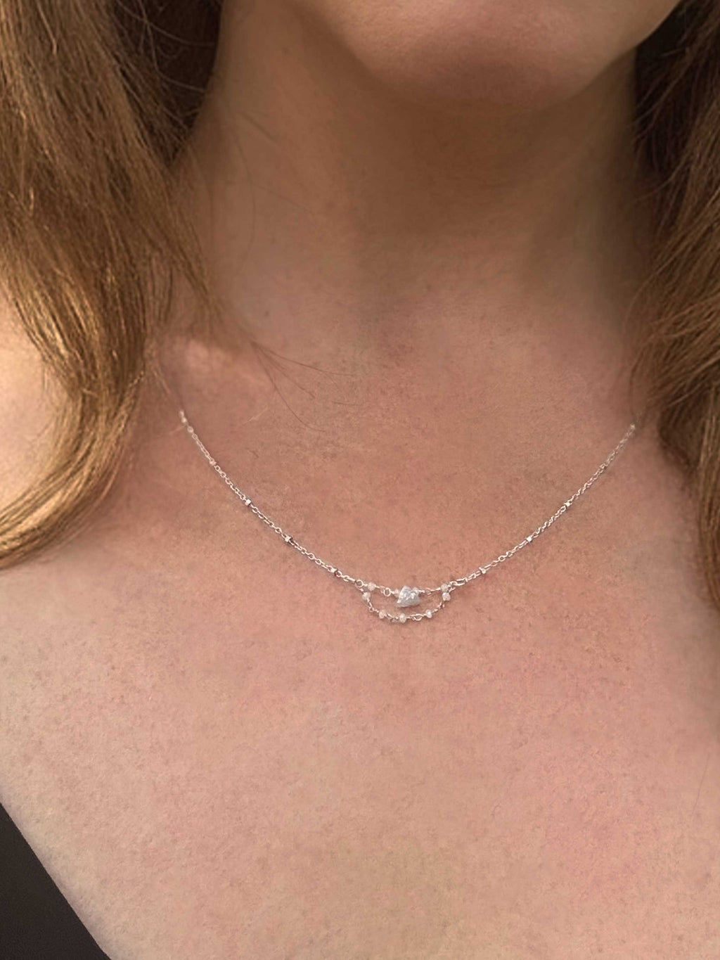 Close-up of a Grey Dawn silver and raw diamond necklace on a person's neck