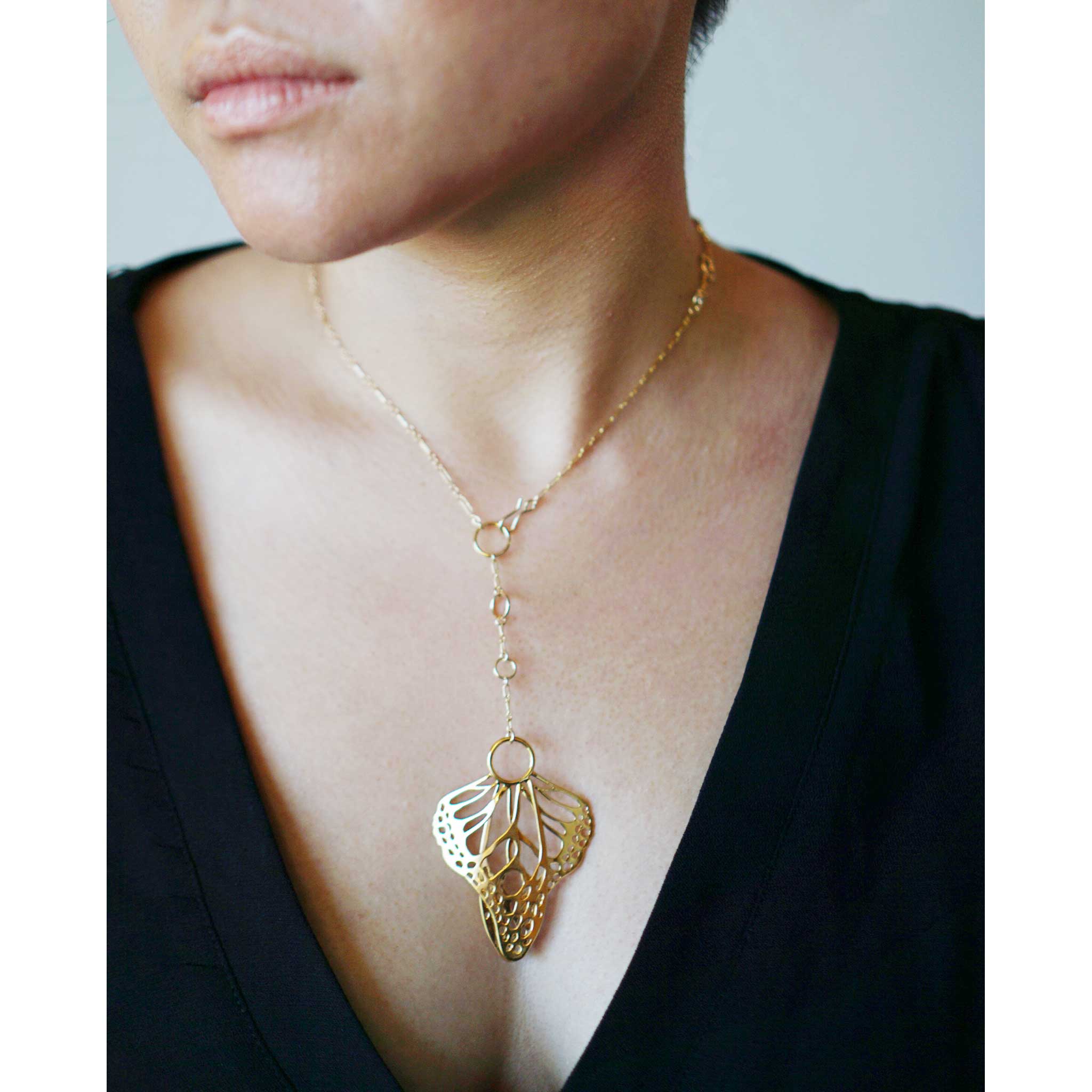 Gold Metamorphosis lariat with butterfly wings  pendant worn by a model