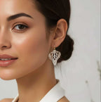 Woman wearing silver handmade butterfly wing earrings with 14k gold ear wires over a blurred background | Camille Torres Designs