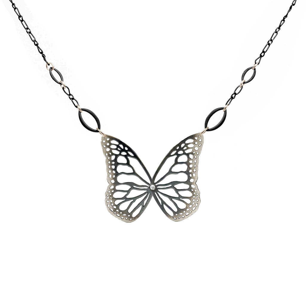 Black and silver Butterfly-shaped pendant with diamond on a chain against a white background
