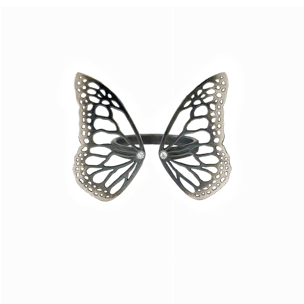 Migration butterfly ring in oxidized sterling silver with intricate cutout wing pattern, 1-inch adjustable band and Diamond accents over a white background | Camille Torres Designs