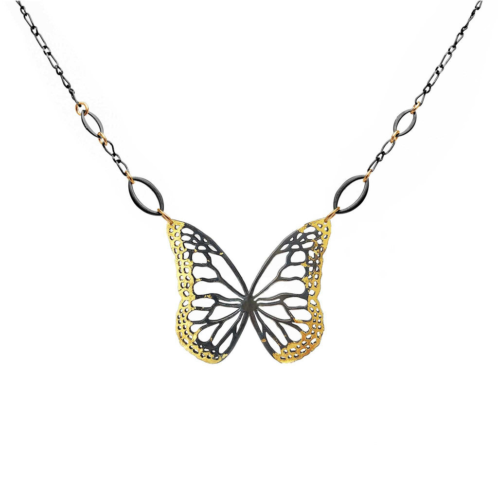 Butterfly necklace with mixed metal gold and black design on a white background