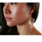 Close-up of a woman wearing a silver Overwinter chandelier butterfly earring with a white background