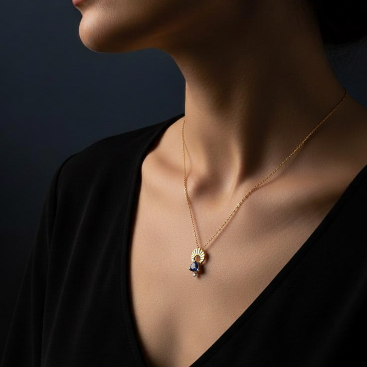 Close-up of woman wearing a 14k Gold Moon charm necklace with a trillion tanzanite and diamond on a dark background | Camille Torres Designs