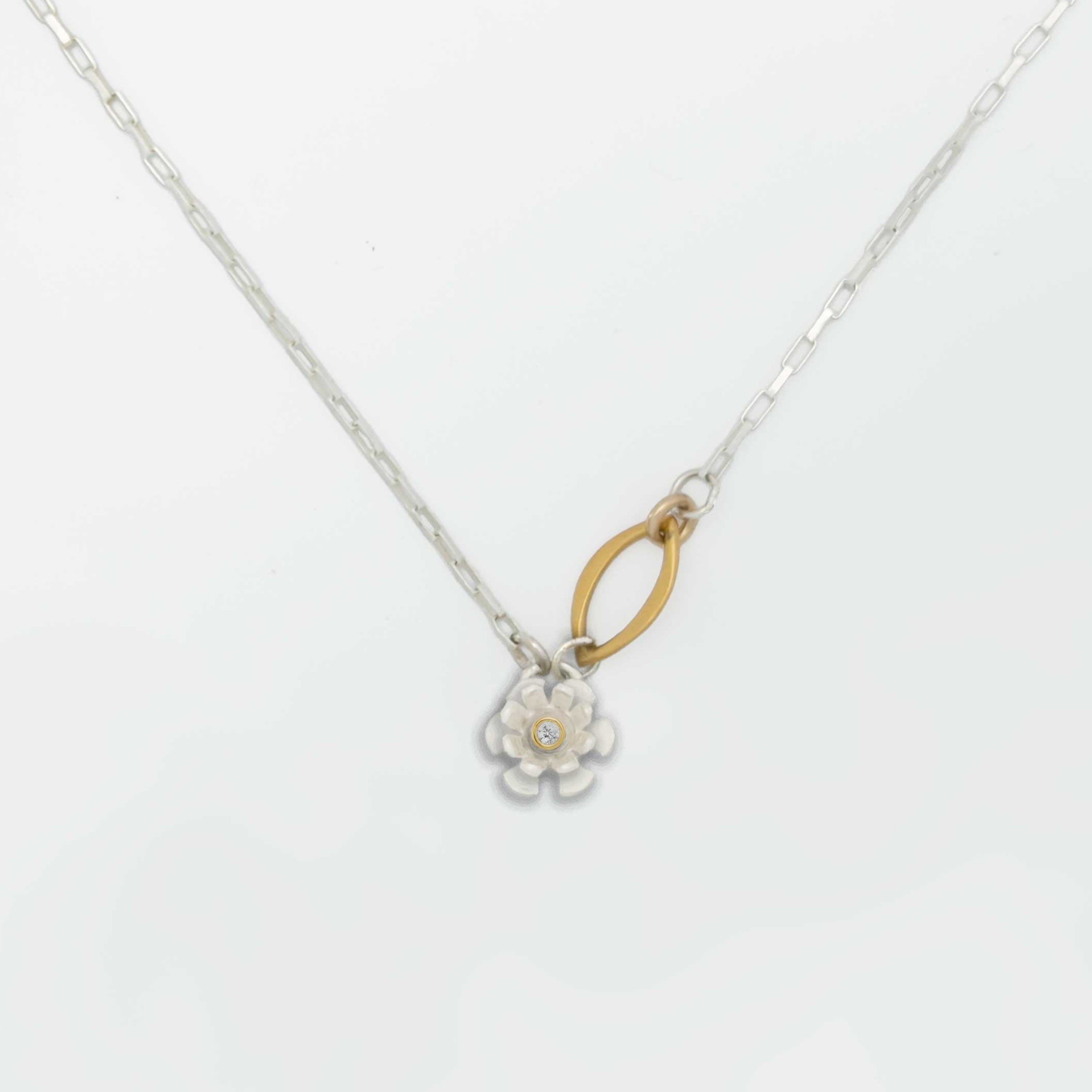 Flower pendant mixed metal necklace with a silver floral pendant and a diamond center set in gold on a white background | Camille Torres Designs