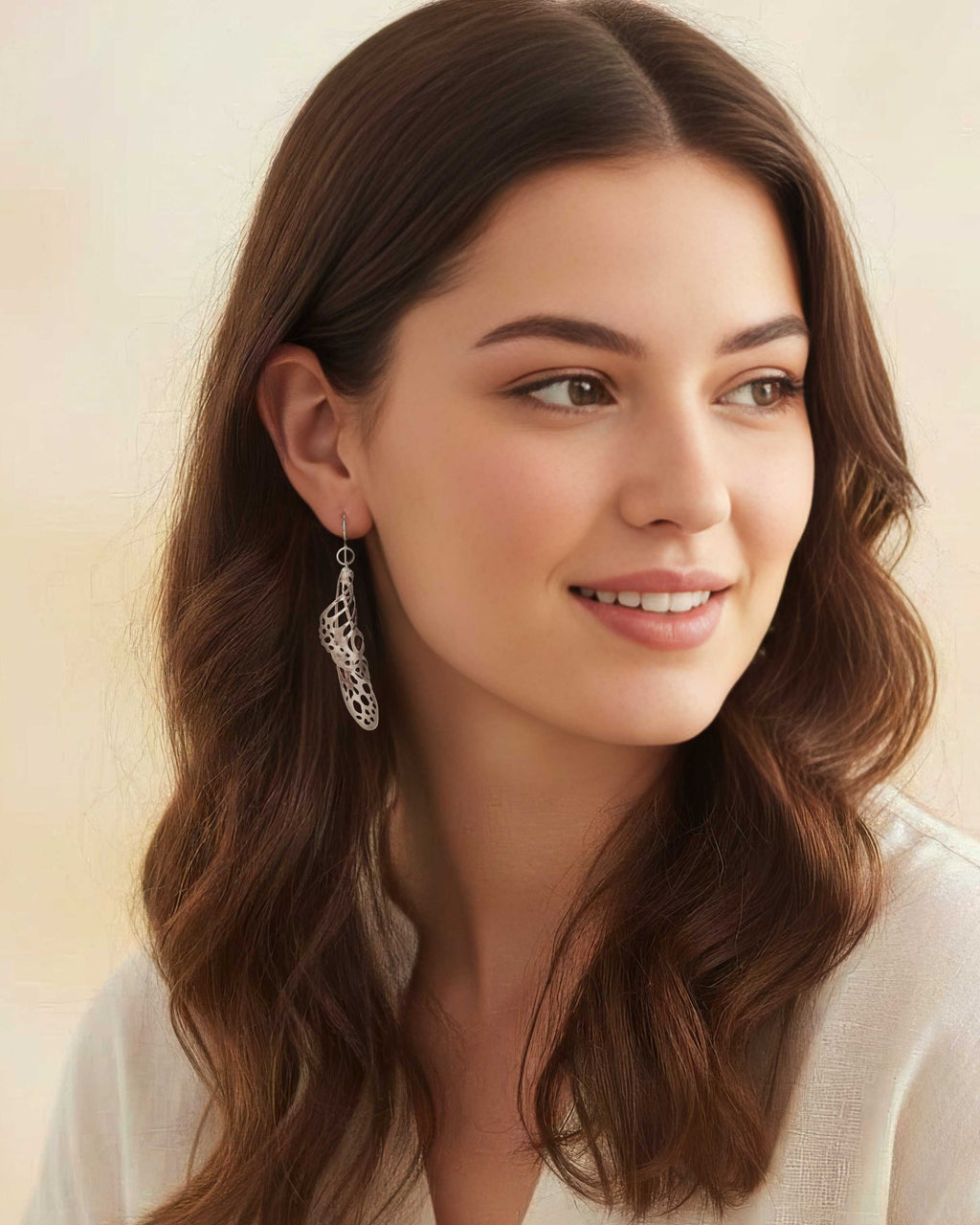 Woman wearing Chrysalis silver drop butterfly earrings and a white blouse with a blurred background