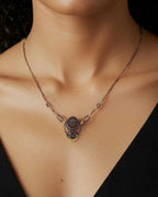 Cocoon butterfly necklace with gold and  sterling silver keum-boo pendant worn by a woman against a black background 