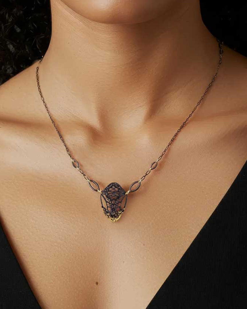 Cocoon butterfly necklace with gold and  sterling silver keum-boo pendant worn by a woman against a black background 