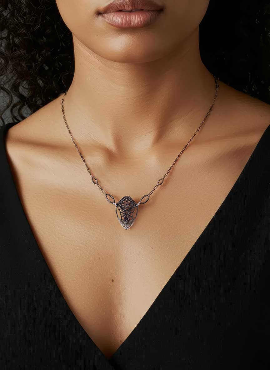 Cocoon butterfly silver necklace with oxidized silver pendant worn by a woman against a black background | Camille Torres Designs