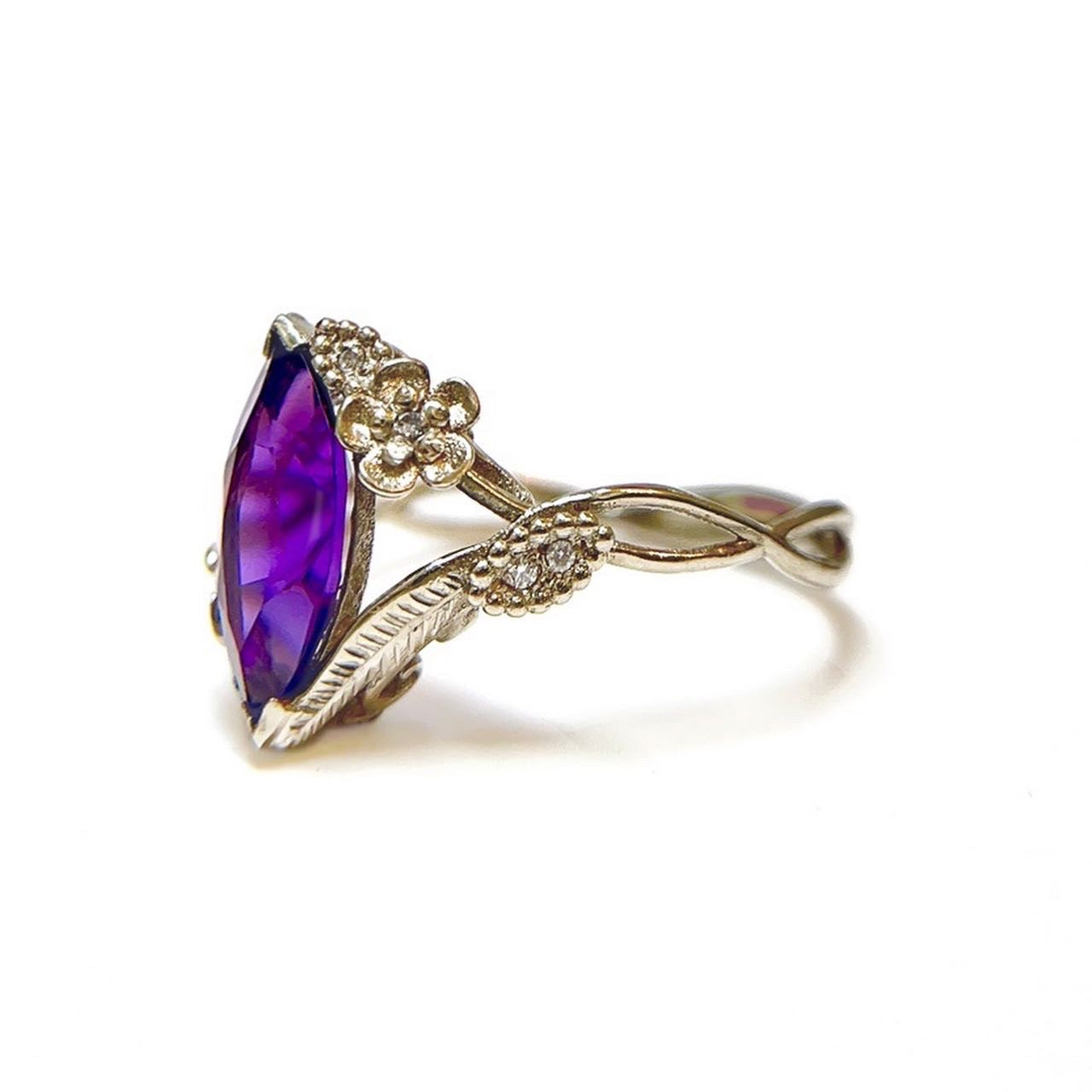Side view of custom floral engagement ring with a colored marquise gem in white gold and diamond accents over a white background | Camille Torres Designs