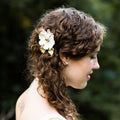 Bride wearing custom silver flower hair pins in a soft curl up-do in front of a blurred nature background | Camille Torres Designs