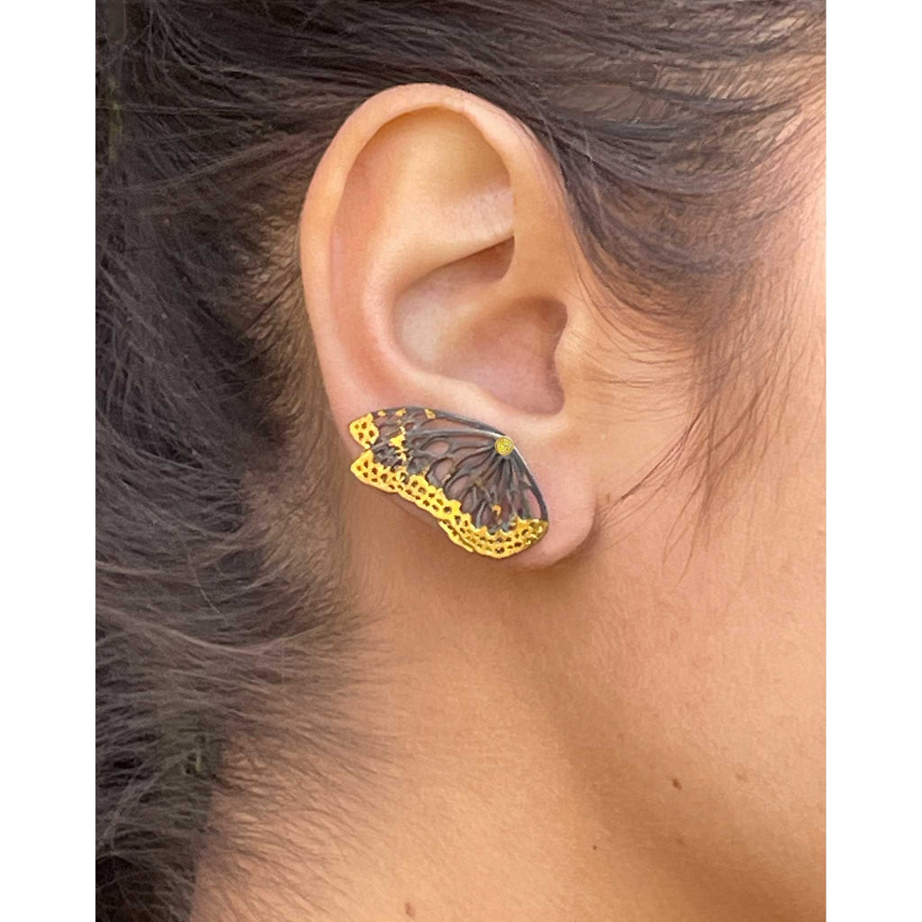 Flight monarch wing keum-boo and sapphire ear climber  worn on an ear with a neutral background
