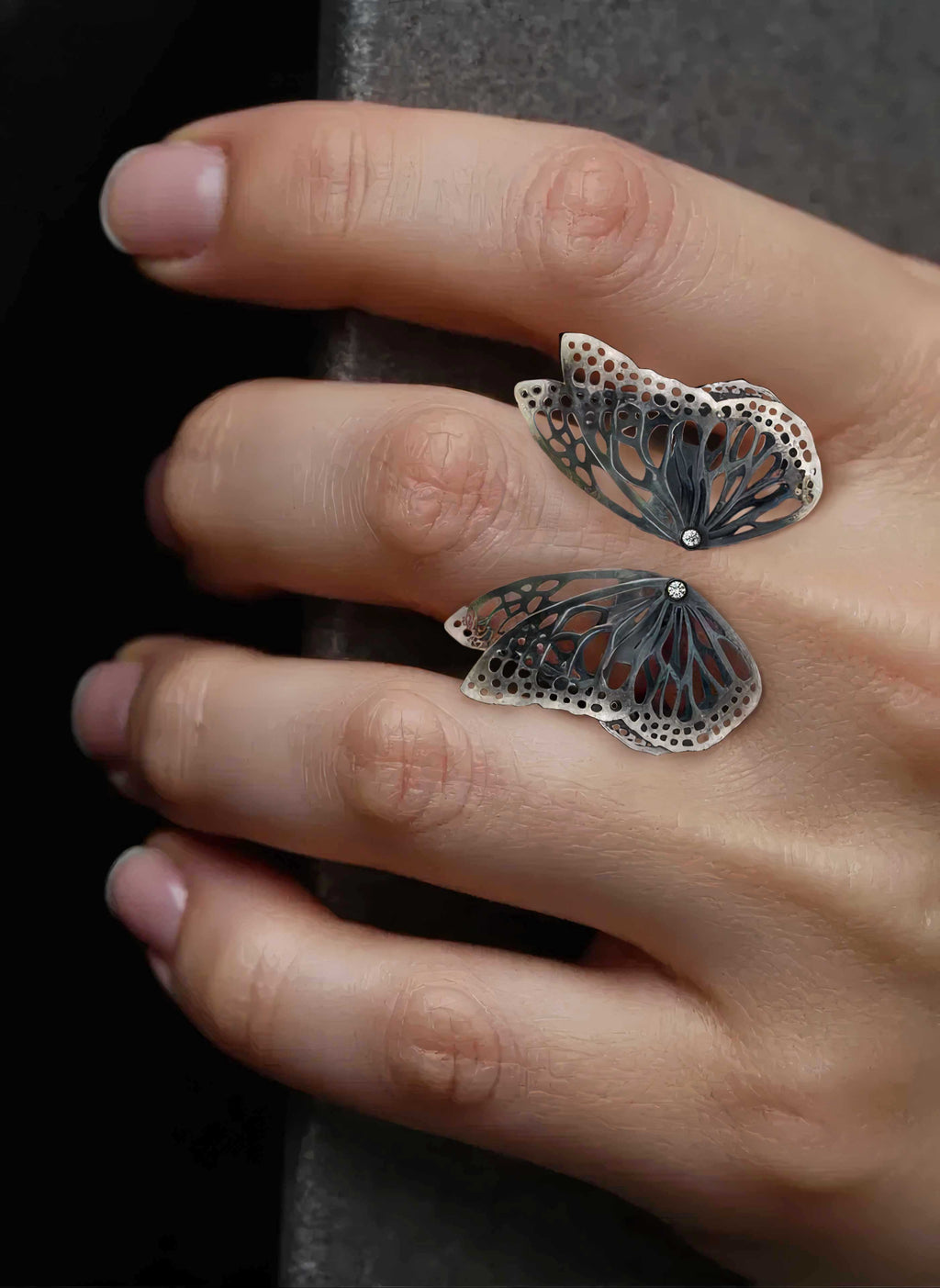 A close-up of a hand wearing a Flight butterfly oxidized silver ring with diamonds | Camille Torres Designs