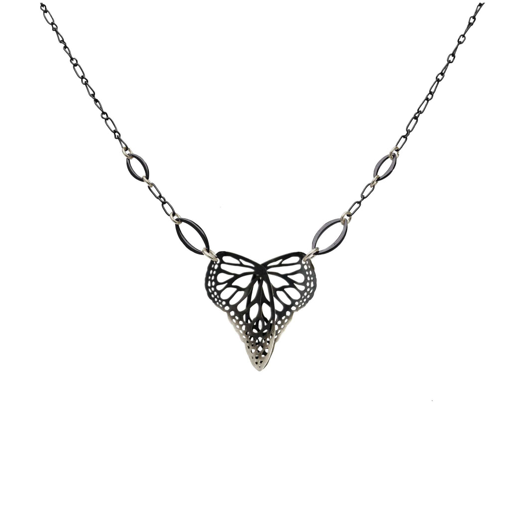 Butterfly in a heart shaped oxidized silver pendant on a chain against a white background | Camille Torres Designs