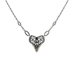 Butterfly in a heart shaped oxidized silver pendant on a chain against a white background | Camille Torres Designs