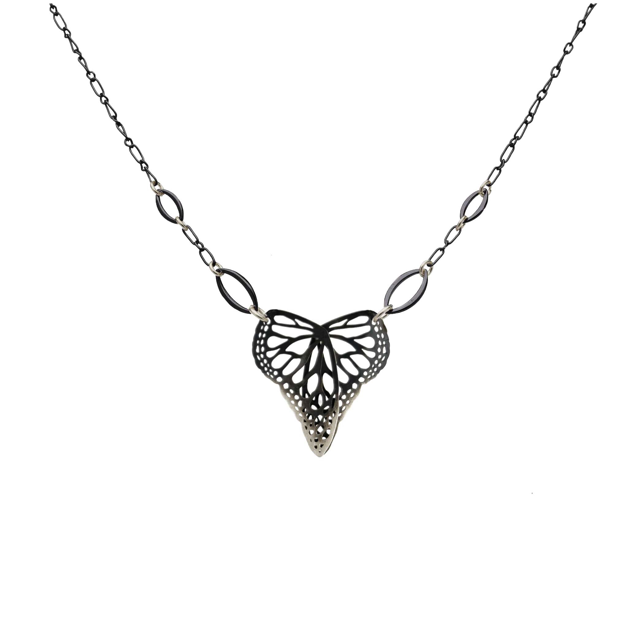 Butterfly in a heart shaped oxidized silver pendant on a chain against a white background | Camille Torres Designs