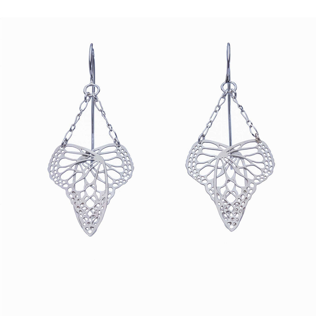 Pair of handcrafted silver heart-shaped butterfly drop earrings suspended from delicate chain on a white background | Camille Torres Designs