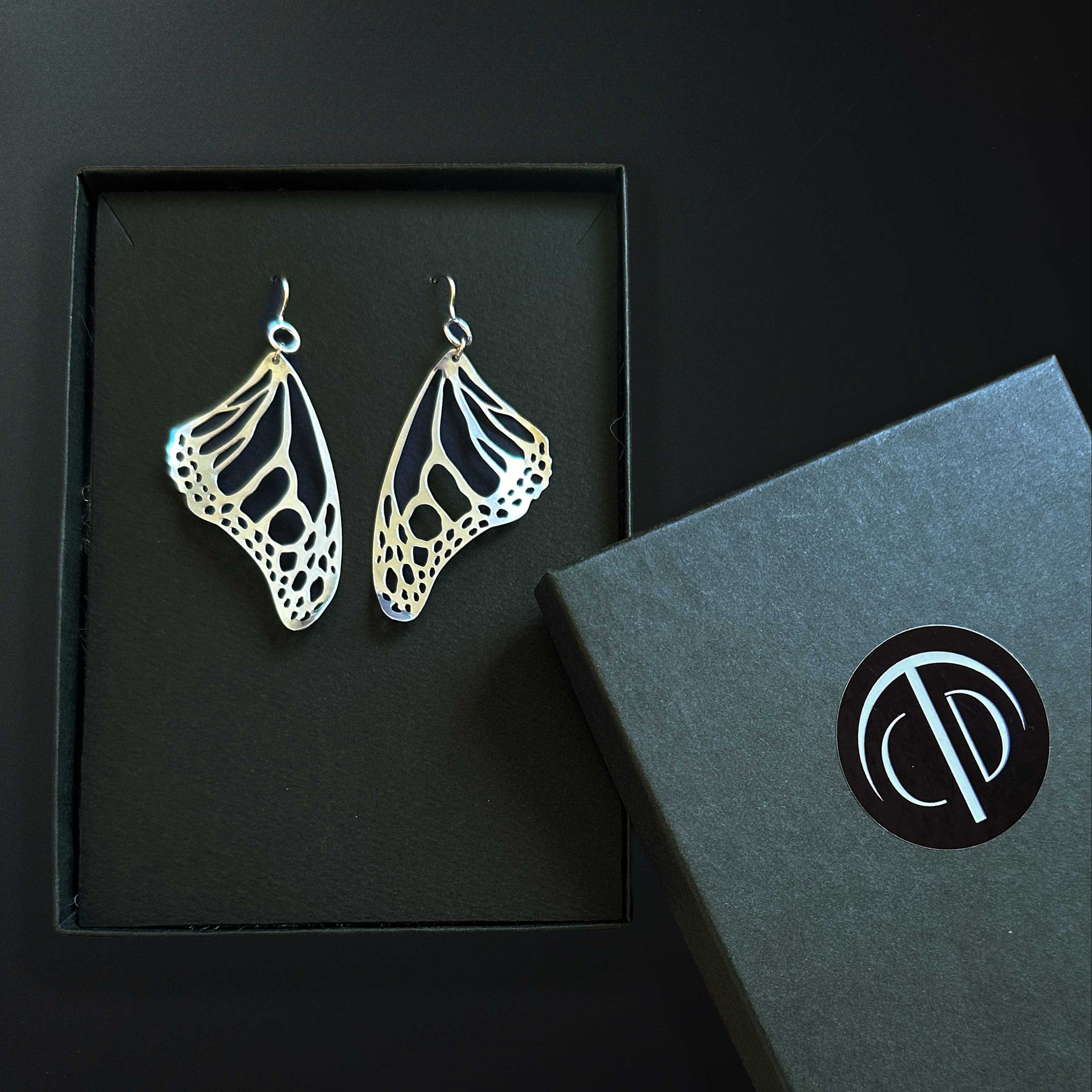 Silver Monarch butterfly earrings in a gift box with a black background