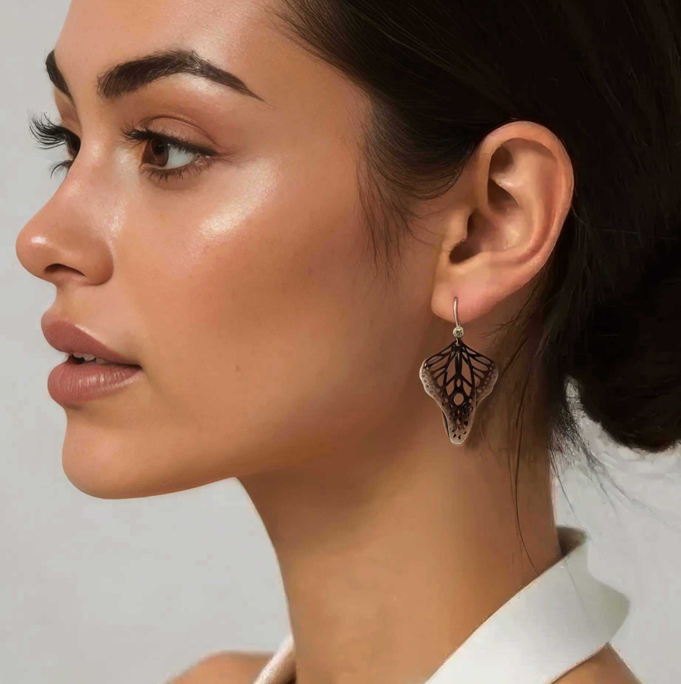 Woman wearing Metamorphosis butterfly dangle earrings in oxidized sterling silver with intricate lace wing pattern, 1.5 inches with diamond accent gold ear wires | Camille Torres Designs