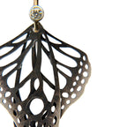 Close-up detail of Metamorphosis butterfly dangle earrings in oxidized silver with intricate lace wing pattern, 2 mm diamond with gold ear wires | Camille Torres Designs