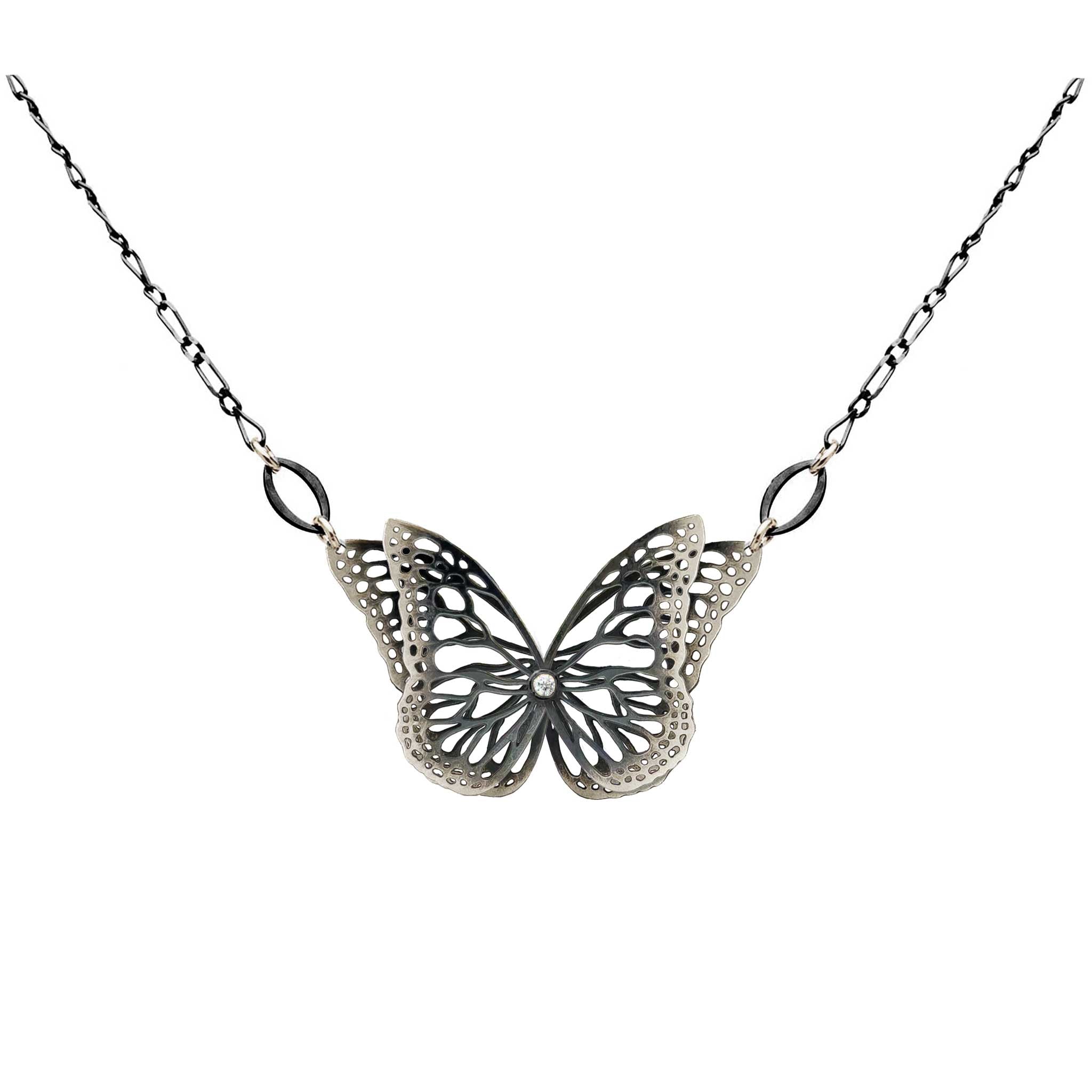 The Migration oxidized silver butterfly pendant necklace with diamond center and overlapping, 2 wing design, suspended from a delicate silver chain against a plain white background.