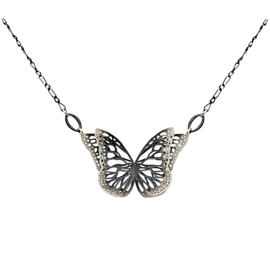 The Migration oxidized silver butterfly pendant necklace with overlapping, 2 wing design, suspended from a delicate silver chain against a plain white background.
