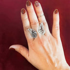 Migration adjustable silver butterfly ring worn on finger, showing dimensional wing wrap over a red background | Camille Torres Designs