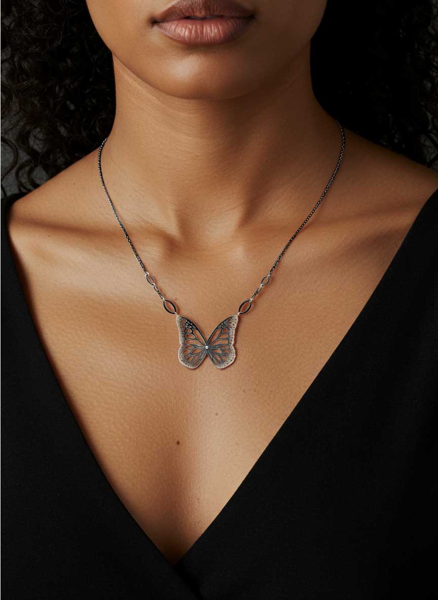 Migration oxidized silver diamond  butterfly necklace on a person wearing a black top against a dark background