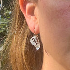 Close up of person wearing small Monarch butterfly dangle earrings in silver with 14k gold ear wires over a white background | Camille Torres Designs