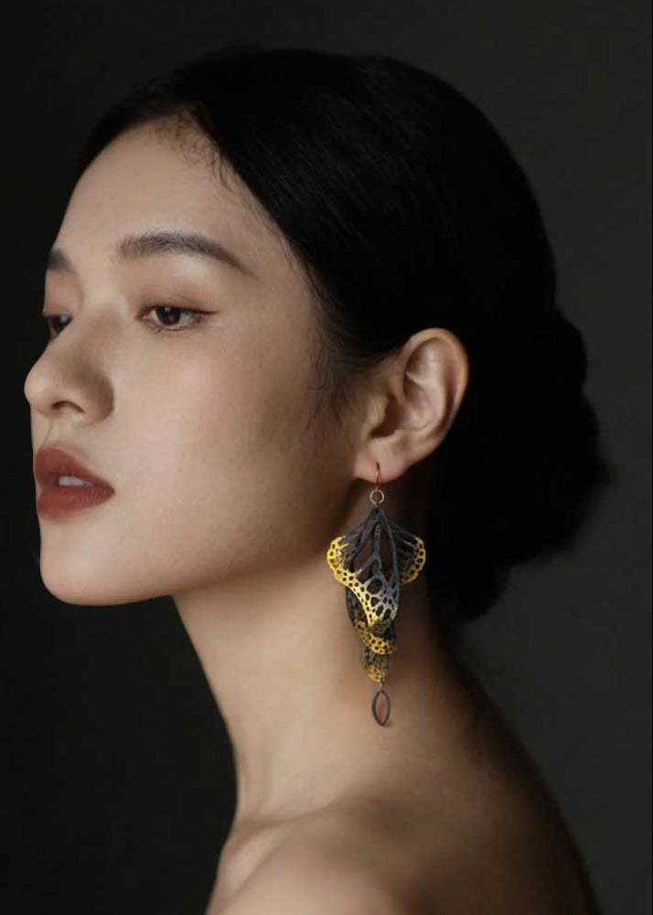 Woman wearing Overwinter monarch butterfly earring in 24k gold keum-boo against a dark background