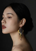 Woman wearing Overwinter monarch butterfly earring in 24k gold keum-boo against a dark background