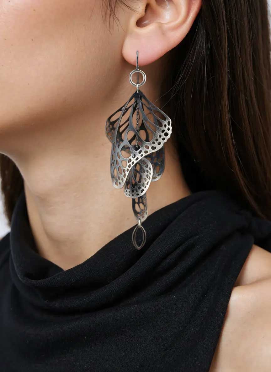 Close-up of a person wearing Overwinter butterfly chandelier oxidized silver earrings 
