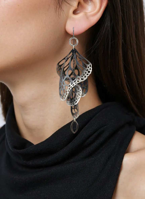 Closeup of woman wearing Overwinter chandelier monarch butterfly earrings in oxidized sterling silver on a white background | Camille Torres Designs