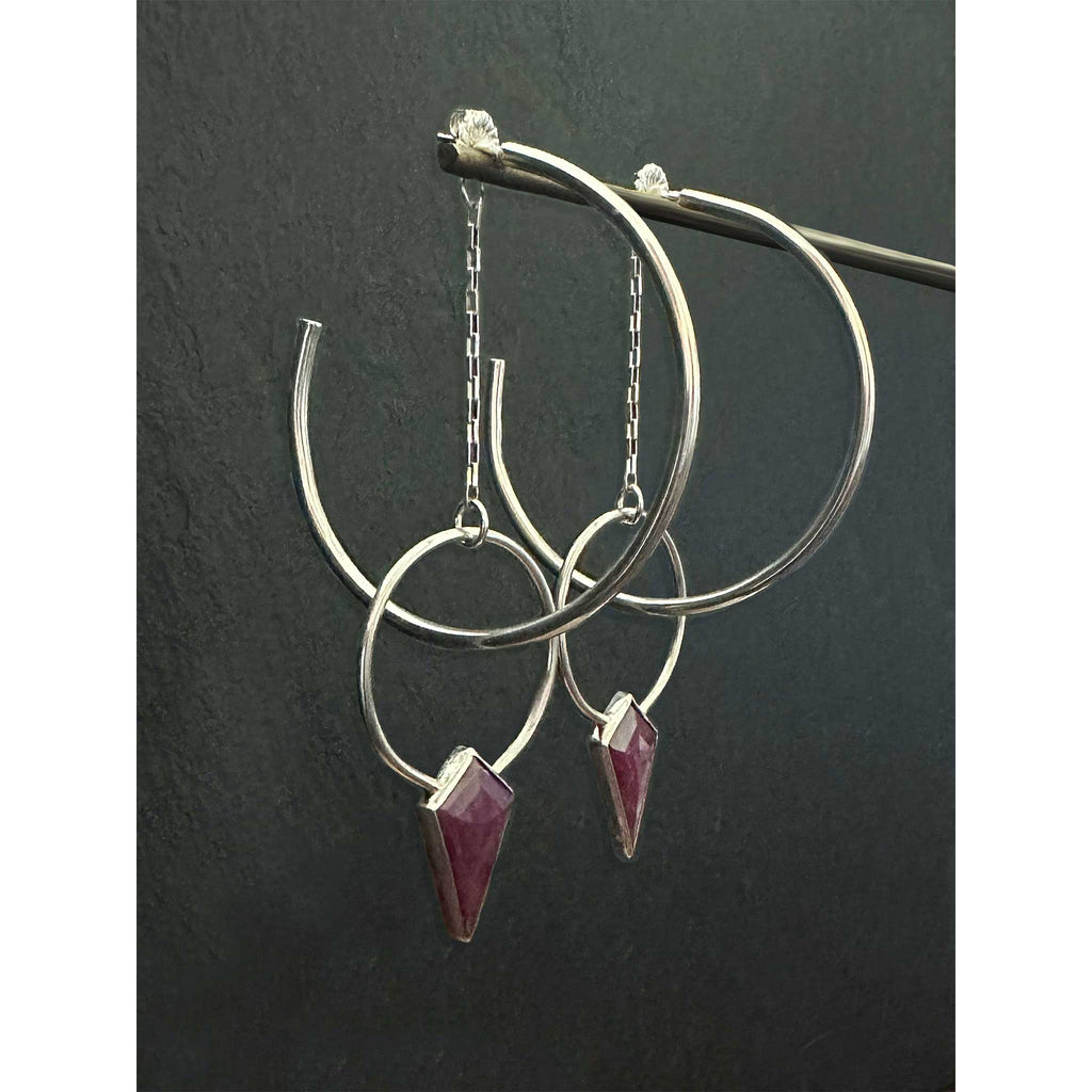 Side view of Ruby Halo Hoops showing dimensional layering of ruby jacket hoop behind 2-inch sterling silver hoop on dark background