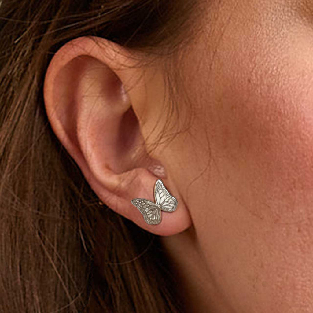 Minimal butterfly silver stud earrings worn by a person with brown hair | Camille Torres Designs