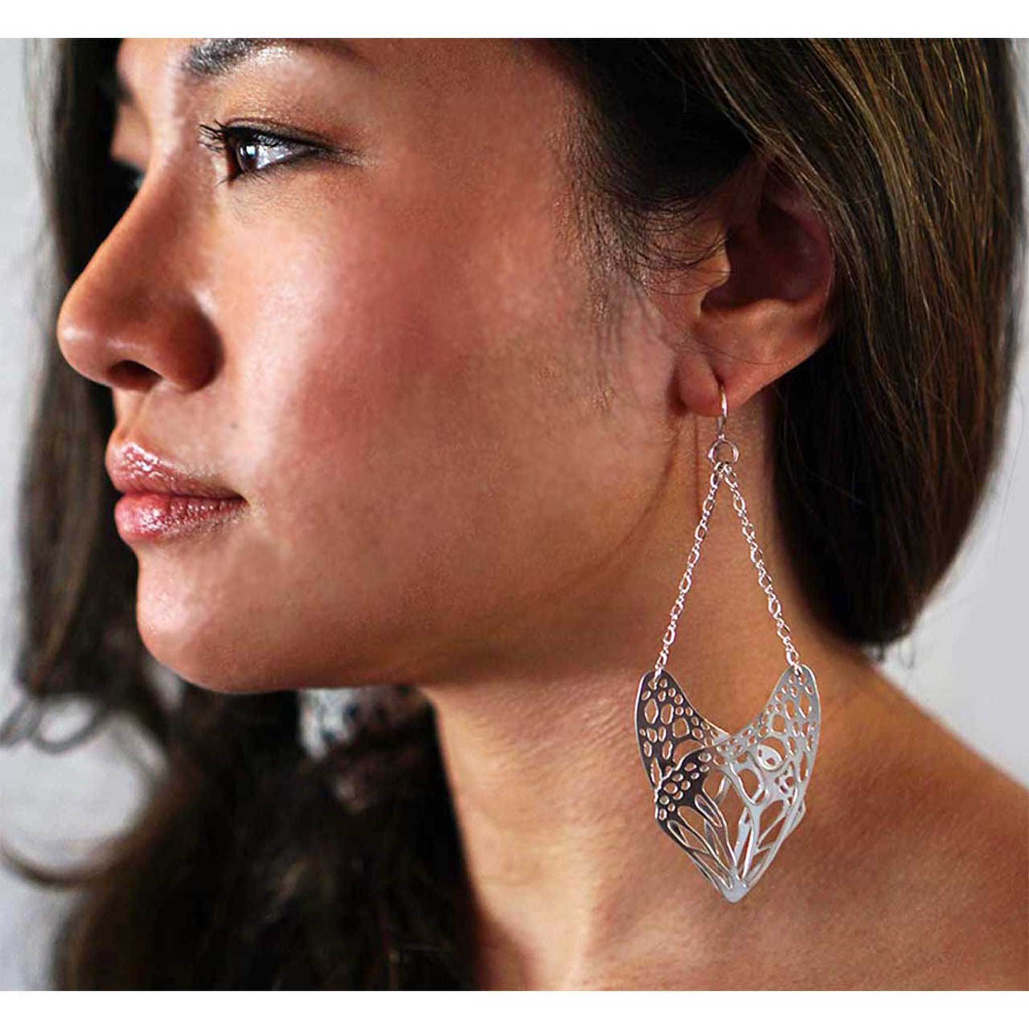 Close-up of a woman wearing a slumber silver butterfly wing dangle earring.