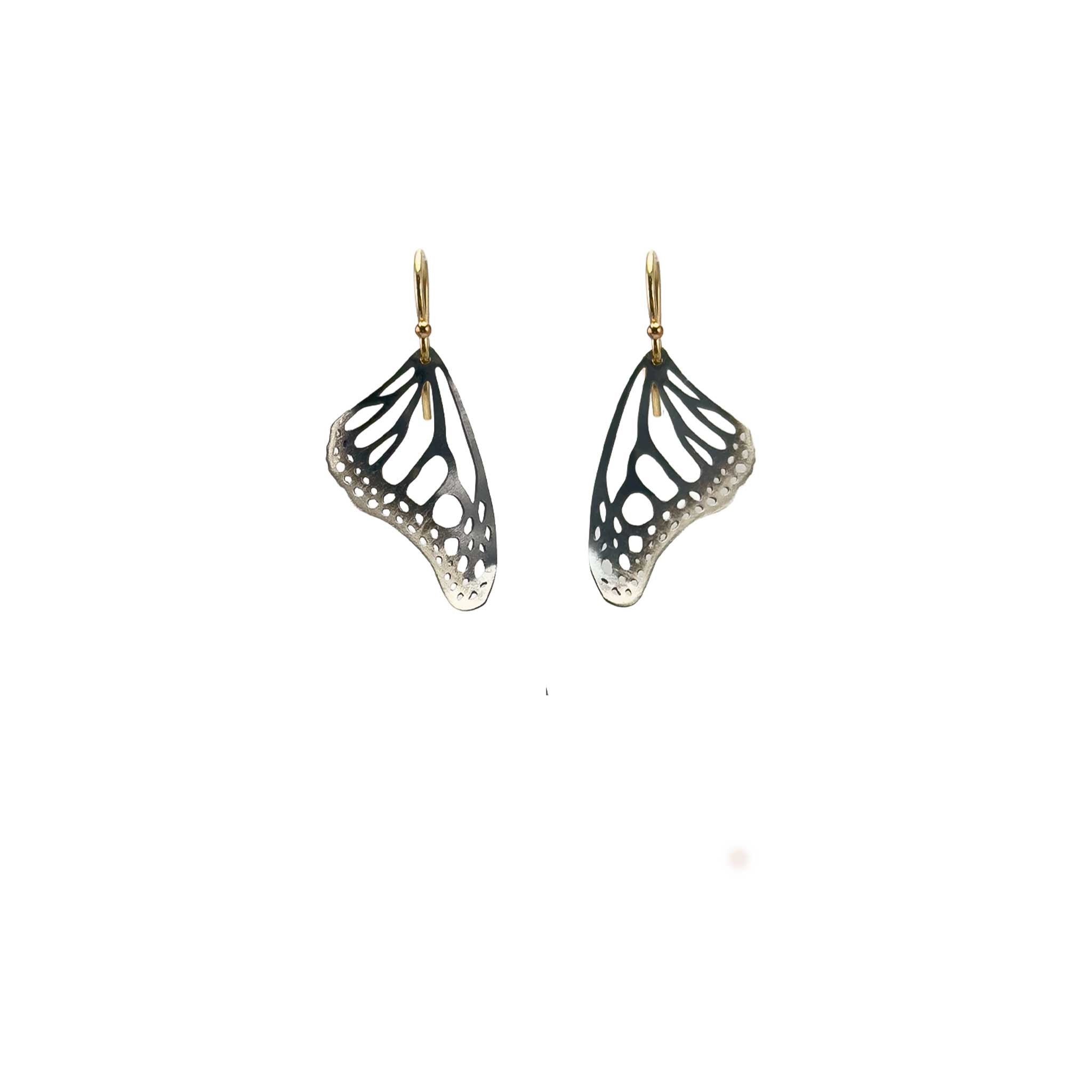 Black Monarch butterfly wing earrings on with gold ear wires on a white background