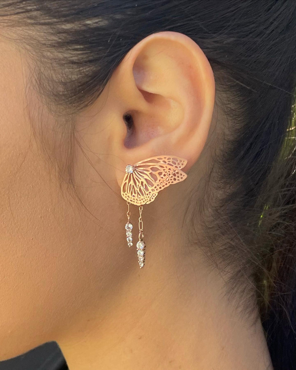 Custom bridal butterfly earring with rose gold and white sapphire in front os a blurred background | Camille Torres Designs