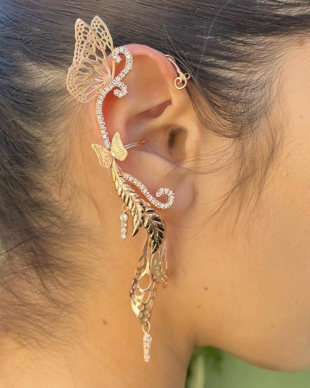 Rose gold bridal butterfly ear cuff with white sapphires worn by a person with blurred background | Camille Torres Designs