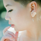 Bespoke bridal butterfly earring with rose gold and white sapphire in front os a blurred background | Camille Torres Designs
